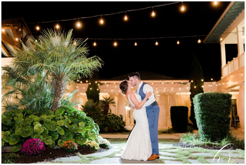 Bride + Groom kissing under twinkle light on wedding day