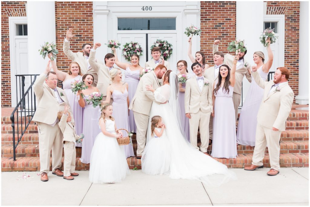 Bridal party poses in front of church on wedding day
