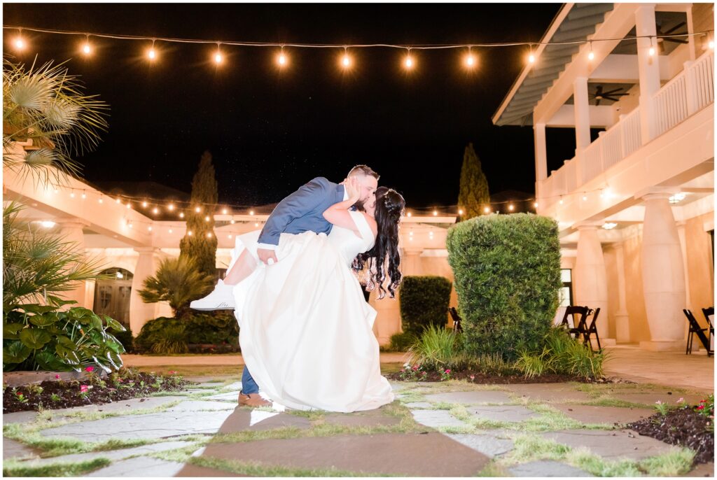 Bride in Groom dipping and kissing under twinkle lights at 21 Main Events. 