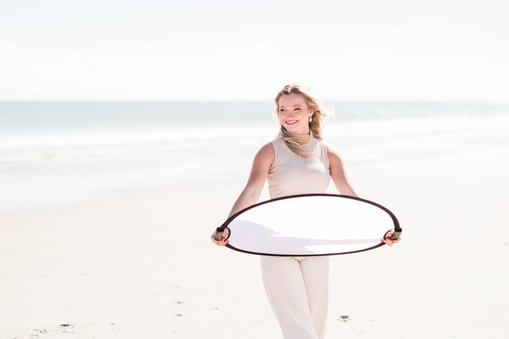 Girl on beach holding reflector - mastering harsh light photos 