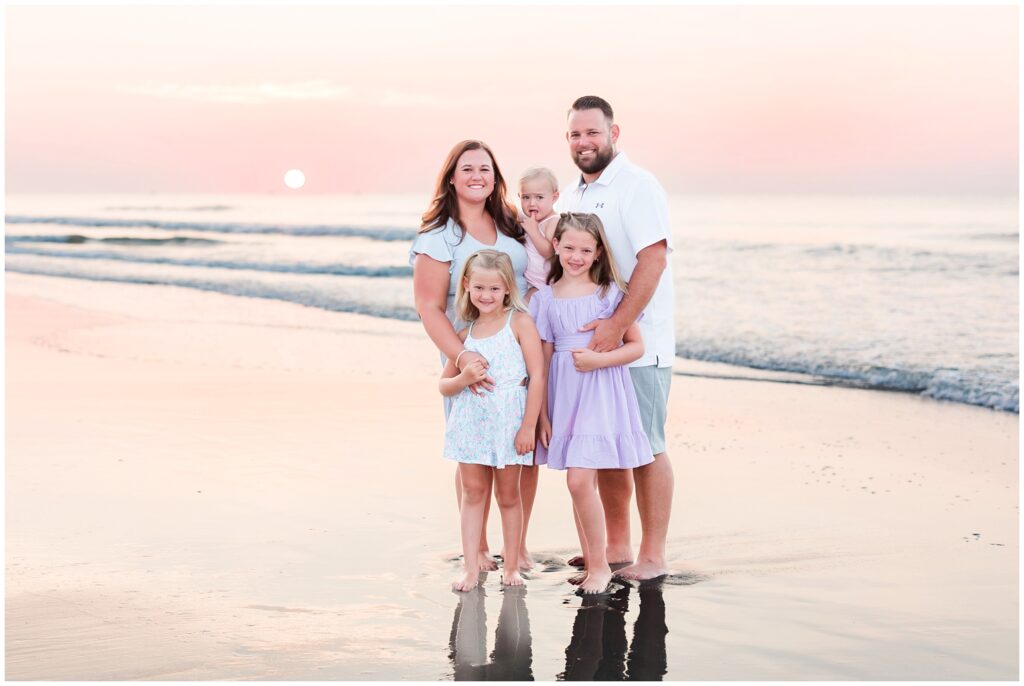 Family of five posing on beach during sunrise photoshoot