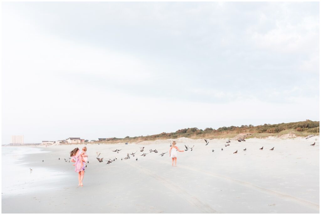 girls chasing birds on beach