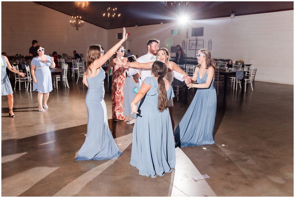 Bride and bridal party dancing in beautiful barn venue. 