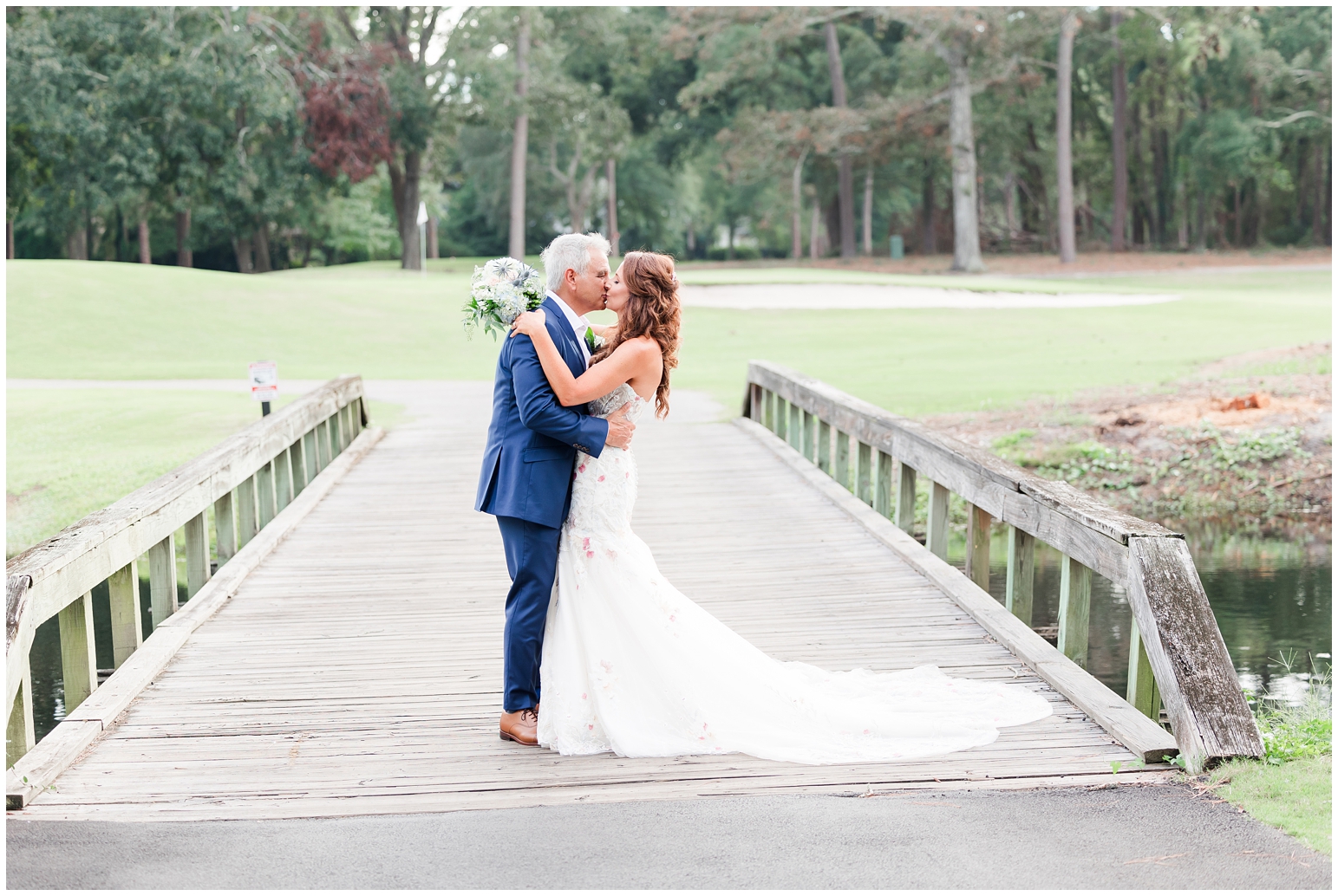 married couple kissing on a bridge