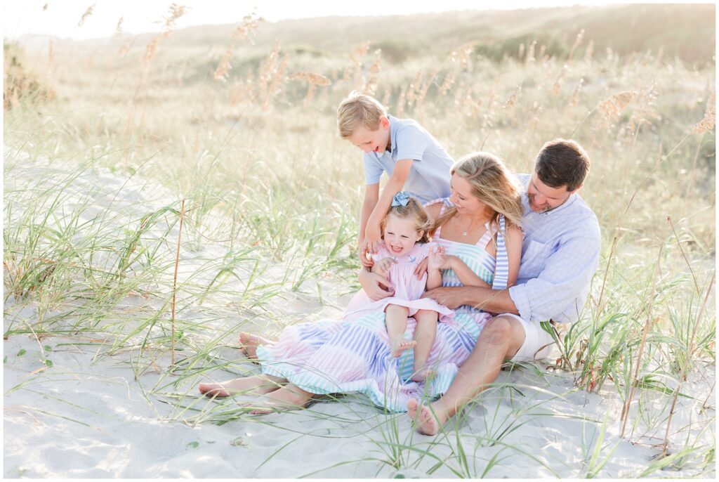 Family of 4 on beach tickling each other for fun family photos 