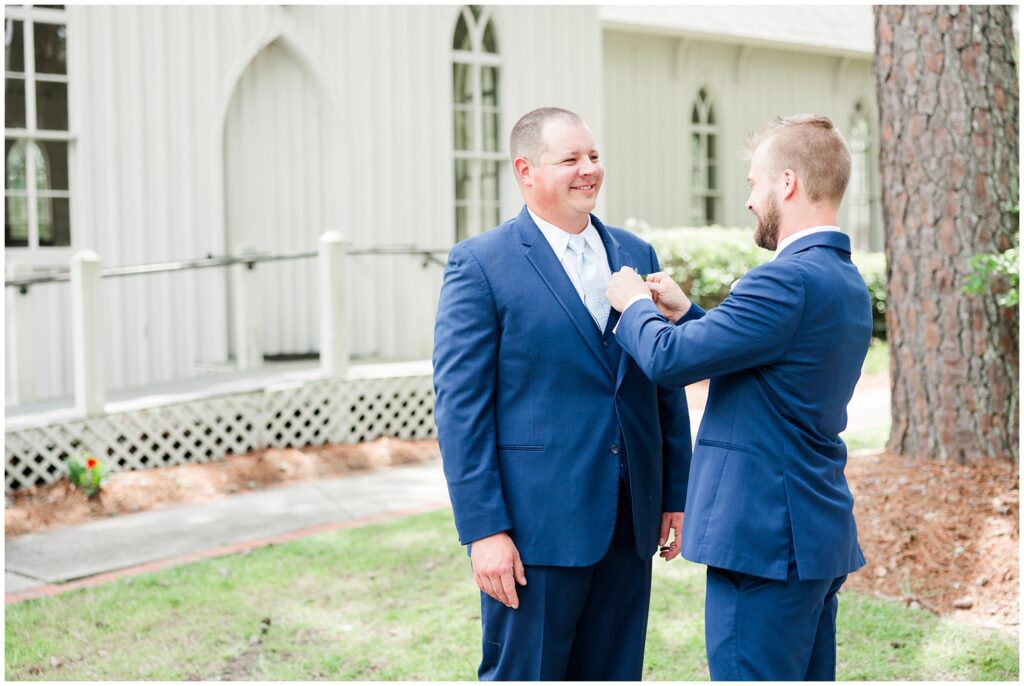 Groomsmen helping groom with his jacket