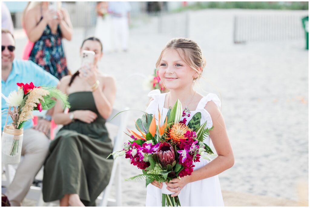 Beach wedding setup with florals and ocean backdrop flower girl