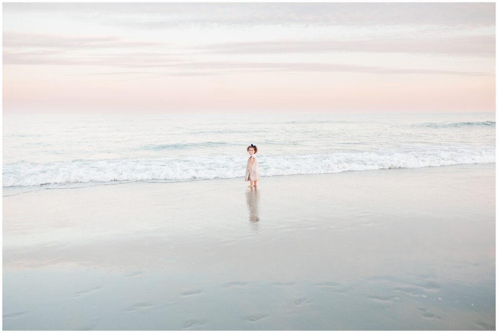 little girl on the beach posing for photo during sunset 